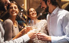 Wine of the Month Delivery shows friends, two ladies and a gentleman enjoying each other's company with a glass of wine.