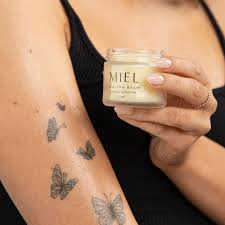 Lady with delicate tattoo showing the organic balm revitalize skin care prevents scabbing